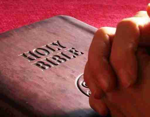 Faith in God . Folded hands on the Holy Bible
